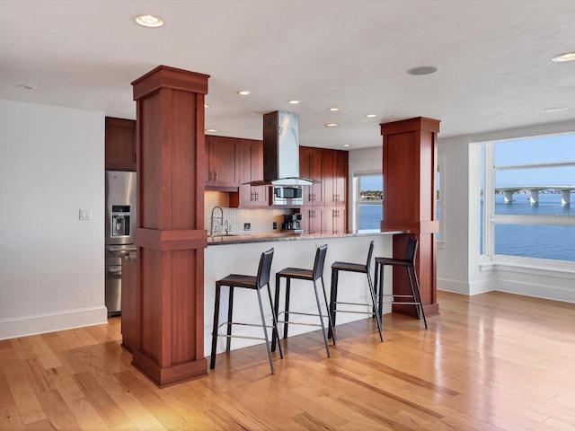 226 Golden Gate Pt Unit 63, Sarasota, FL 34236 - kitchen featuring island range hood, a sink, stainless steel appliances, tasteful backsplash, and light wood finished floors