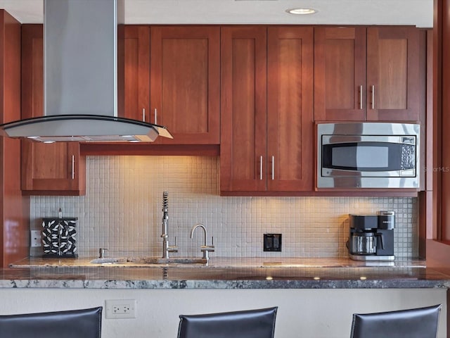 226 Golden Gate Pt Unit 63, Sarasota, FL 34236 - kitchen with wall chimney exhaust hood, stainless steel microwave, a sink, and decorative backsplash