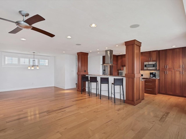 226 Golden Gate Pt Unit 63, Sarasota, FL 34236 - kitchen featuring stainless steel microwave, ventilation hood, a breakfast bar area, decorative columns, and ceiling fan