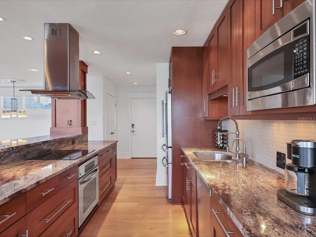 226 Golden Gate Pt Unit 63, Sarasota, FL 34236 - kitchen featuring appliances with stainless steel finishes, island range hood, a sink, decorative backsplash, and light wood-style flooring
