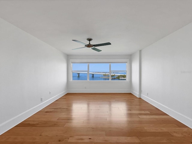 226 Golden Gate Pt Unit 63, Sarasota, FL 34236 - spare room featuring baseboards, ceiling fan, light wood-style flooring, and a water view
