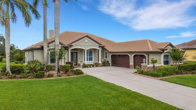 385 165th Ct NE, Bradenton, FL 34212 - mediterranean / spanish house with an attached garage, stucco siding, a tile roof, a front yard, and a chimney