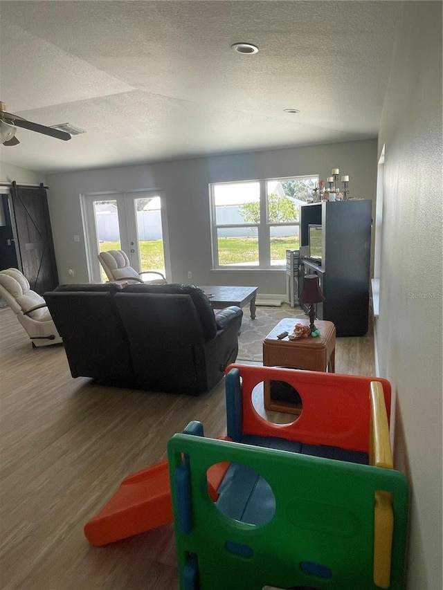 5094 Bunyan St, Sarasota, FL 34232 - living area featuring healthy amount of natural light, wood finished floors, a textured ceiling, and a barn door