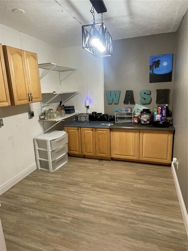 5094 Bunyan St, Sarasota, FL 34232 - kitchen featuring light wood finished floors, dark countertops, open shelves, baseboards, and hanging light fixtures