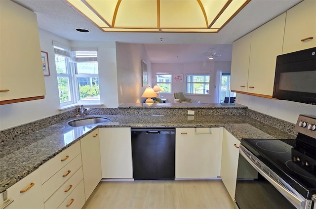 1311 Siesta Bayside Dr Unit 1311-A, Sarasota, FL 34242 - kitchen with black appliances, a sink, dark stone countertops, and light wood-style flooring