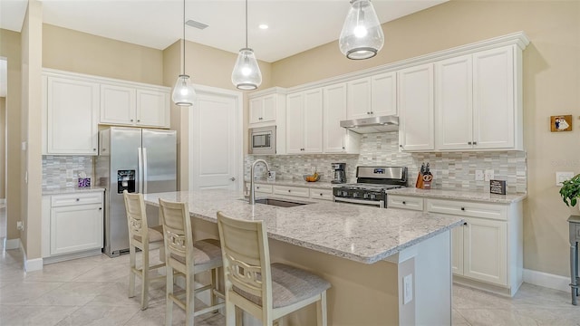 kitchen featuring appliances with stainless steel finishes, under cabinet range hood, a sink, decorative backsplash, and white cabinetry