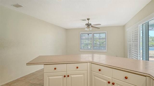 4361 Pompano Ln, Palmetto, FL 34221 - kitchen featuring ceiling fan, light tile patterned flooring, light countertops, white cabinetry, and baseboards