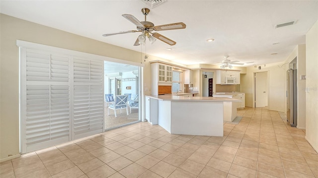 4361 Pompano Ln, Palmetto, FL 34221 - kitchen with freestanding refrigerator, a ceiling fan, a peninsula, glass insert cabinets, and white microwave