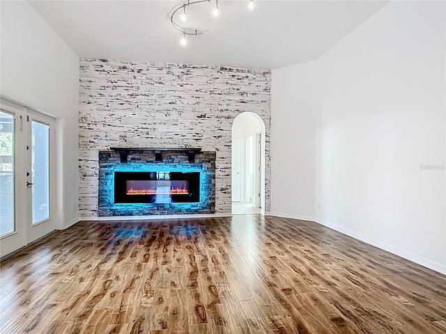 4239 Corso Venetia Blvd, Venice, FL 34293 - unfurnished living room featuring wood finished floors, arched walkways, and a tile fireplace