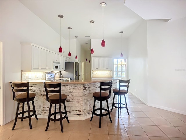 4239 Corso Venetia Blvd, Venice, FL 34293 - kitchen featuring white microwave, stainless steel fridge with ice dispenser, high vaulted ceiling, a peninsula, and light tile patterned floors