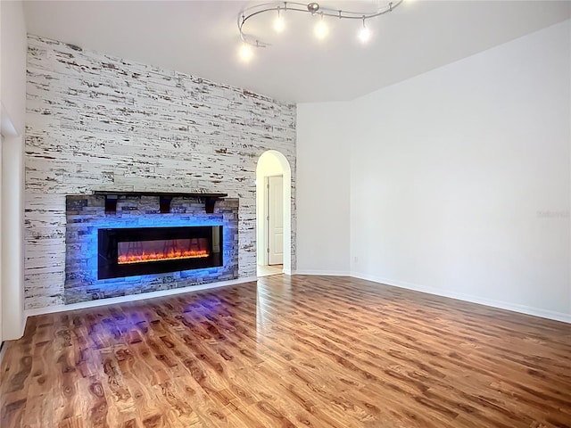 4239 Corso Venetia Blvd, Venice, FL 34293 - unfurnished living room featuring wood finished floors, a fireplace, baseboards, and arched walkways