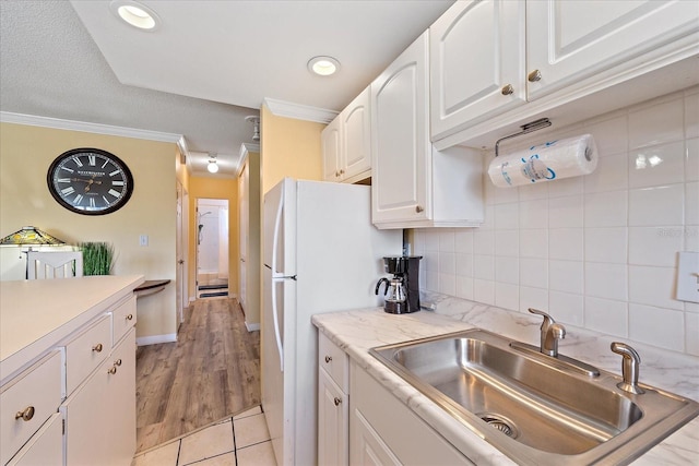 475 Benjamin Franklin Dr Unit 211, Sarasota, FL 34236 - kitchen featuring a sink, crown molding, white cabinets, light countertops, and light tile patterned floors