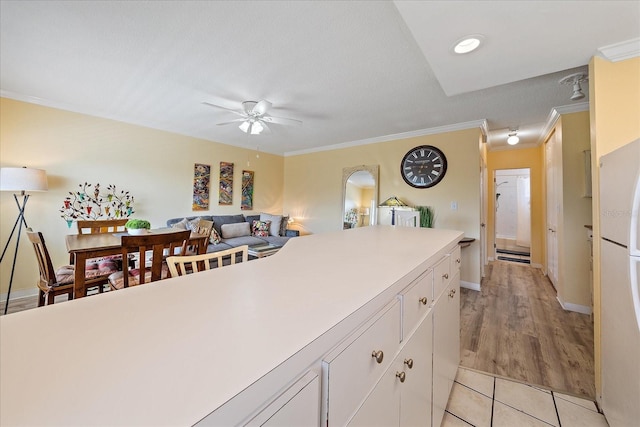 475 Benjamin Franklin Dr Unit 211, Sarasota, FL 34236 - kitchen featuring ceiling fan, white cabinetry, crown molding, light tile patterned floors, and light countertops