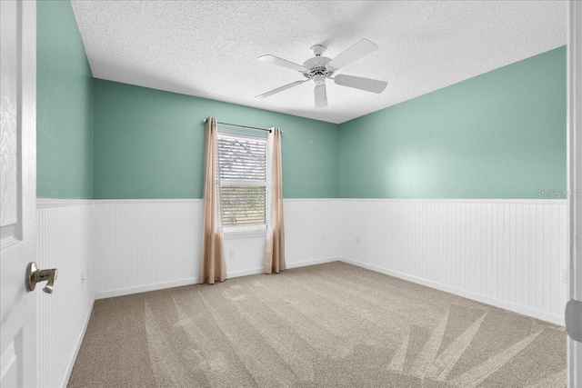 10001 289th St E, Myakka City, FL 34251 - spare room featuring a wainscoted wall, a ceiling fan, a textured ceiling, and carpet flooring
