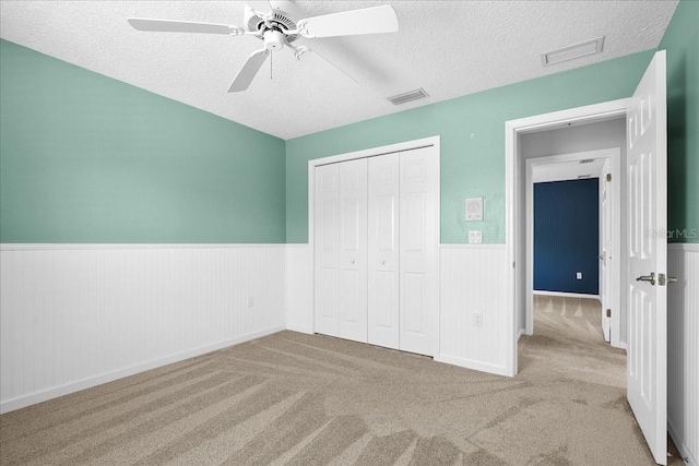 10001 289th St E, Myakka City, FL 34251 - unfurnished bedroom featuring a wainscoted wall, a textured ceiling, a closet, carpet flooring, and a ceiling fan