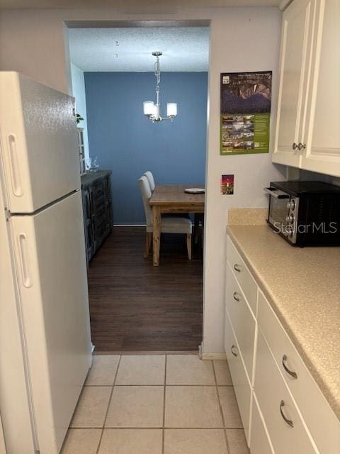 2218 Orange Blossom Ln Unit 0, Bradenton, FL 34207 - kitchen with freestanding refrigerator, a chandelier, light tile patterned floors, light countertops, and white cabinetry