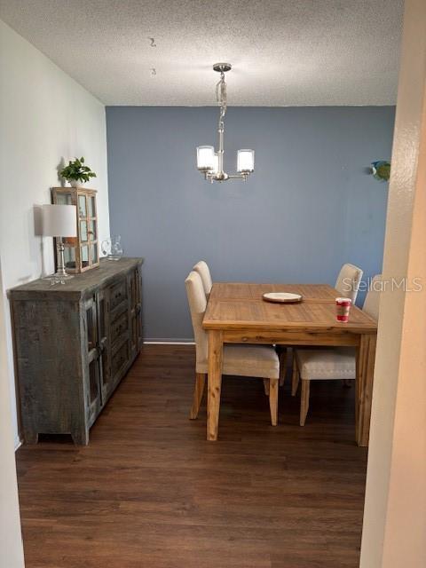 2218 Orange Blossom Ln Unit 0, Bradenton, FL 34207 - dining room featuring dark wood-type flooring, a chandelier, a textured ceiling, and baseboards