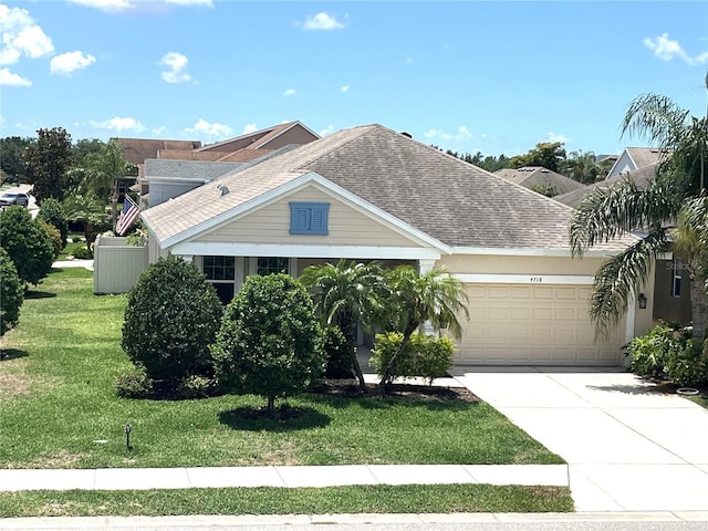 view of front of home with a shingled roof, a garage, concrete driveway, and a front yard