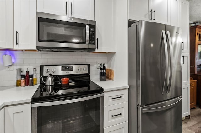 kitchen featuring appliances with stainless steel finishes, white cabinetry, tasteful backsplash, and light wood finished floors