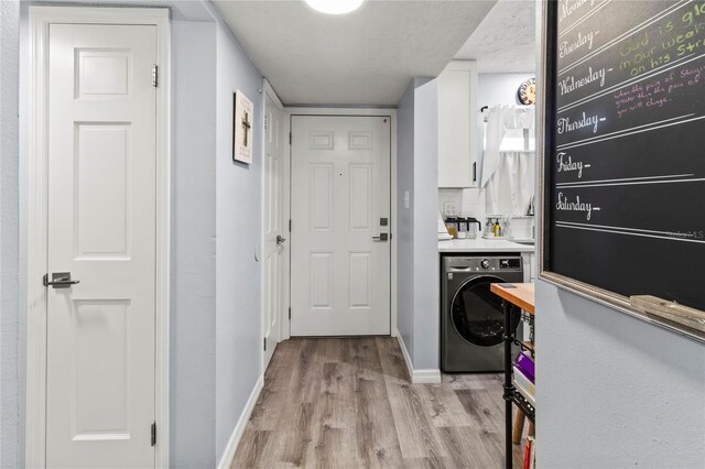 laundry area featuring washer / dryer, light wood-style flooring, and baseboards