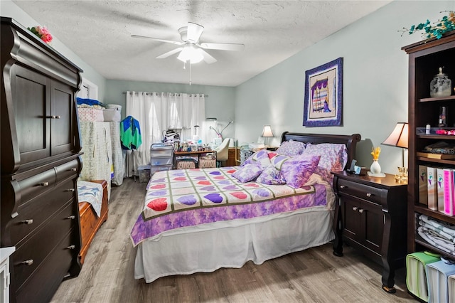 bedroom with light wood-style flooring, a textured ceiling, and ceiling fan