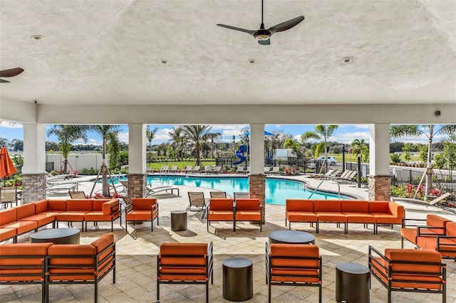 view of patio featuring an outdoor hangout area, fence, ceiling fan, and a community pool