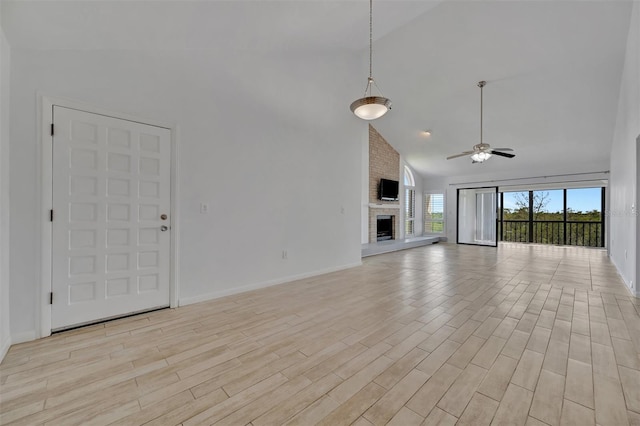 8710 54th Ave W Unit 8710, Bradenton, FL 34210 - unfurnished living room featuring high vaulted ceiling, a ceiling fan, light wood-style flooring, a brick fireplace, and baseboards