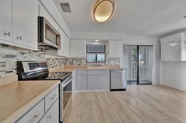 8710 54th Ave W Unit 8710, Bradenton, FL 34210 - kitchen with appliances with stainless steel finishes, light countertops, tasteful backsplash, white cabinetry, and light wood-style floors