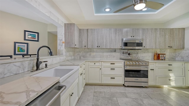 5500 Merrimac Dr, Sarasota, FL 34231 - kitchen featuring stainless steel appliances, decorative backsplash, light stone countertops, a sink, and ceiling fan