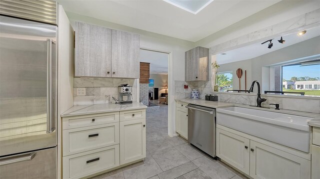 5500 Merrimac Dr, Sarasota, FL 34231 - kitchen with stainless steel appliances, backsplash, light tile patterned floors, light stone countertops, and a sink