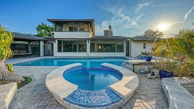 5500 Merrimac Dr, Sarasota, FL 34231 - back of property featuring a balcony, a patio area, a pool with connected hot tub, and a chimney