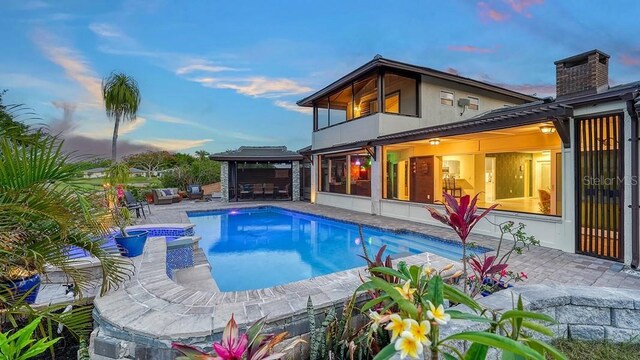 5500 Merrimac Dr, Sarasota, FL 34231 - back of house featuring a balcony, a patio, a pool with connected hot tub, and a chimney