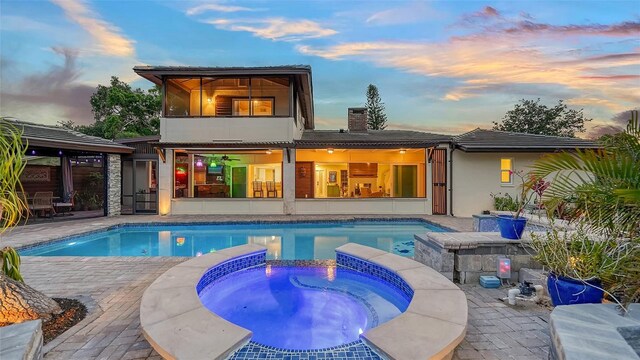 5500 Merrimac Dr, Sarasota, FL 34231 - back of property at dusk featuring a patio area, ceiling fan, a chimney, and a pool with connected hot tub