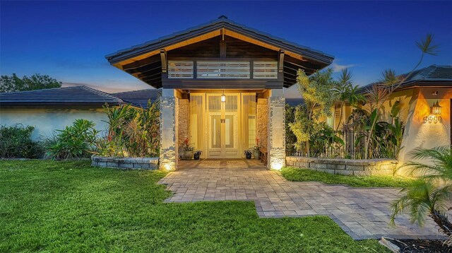 5500 Merrimac Dr, Sarasota, FL 34231 - doorway to property featuring a lawn, a balcony, and stucco siding