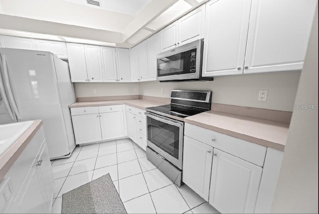 kitchen with stainless steel appliances, white cabinets, light countertops, and light tile patterned flooring