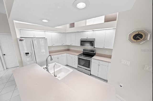 kitchen with stainless steel appliances, a sink, white cabinetry, light countertops, and light tile patterned flooring