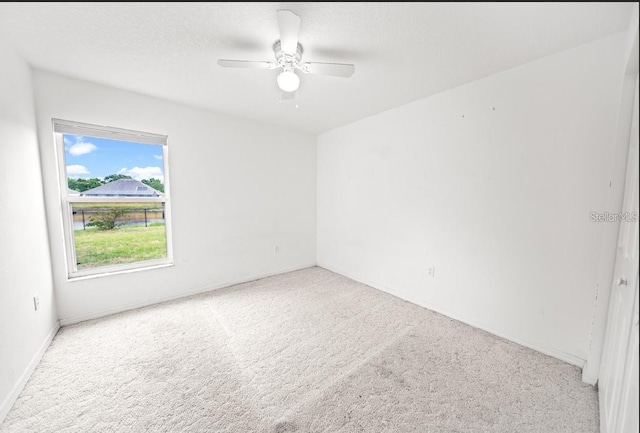 carpeted empty room featuring a ceiling fan and baseboards