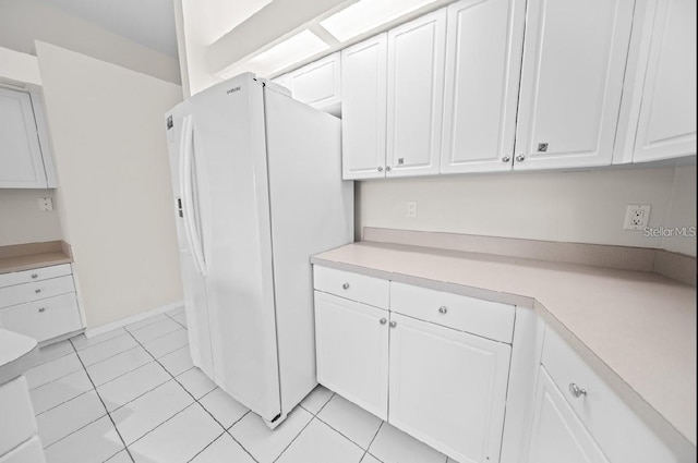 kitchen featuring freestanding refrigerator, white cabinetry, light countertops, and light tile patterned floors