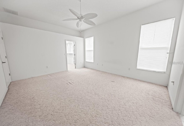 unfurnished room with light colored carpet, a ceiling fan, and baseboards