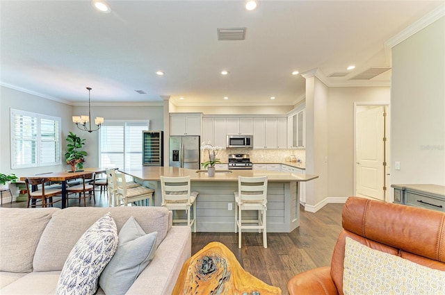 5035 Tobermory Way, Bradenton, FL 34211 - living room with a chandelier, dark wood-type flooring, recessed lighting, baseboards, and crown molding