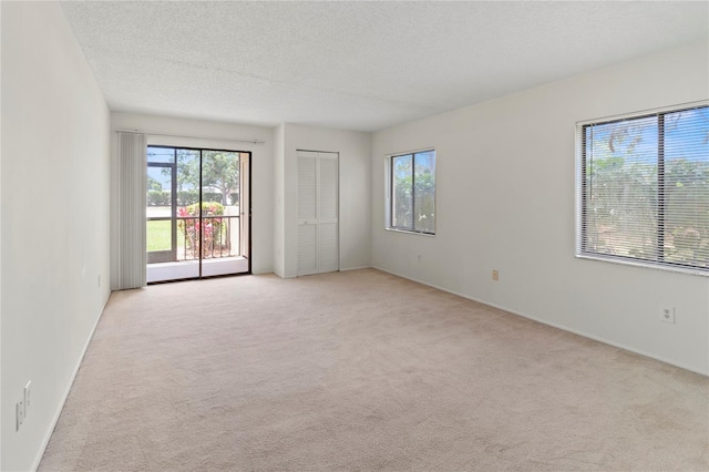 7500 40th Ave W Unit 108, Bradenton, FL 34209 - unfurnished room with healthy amount of natural light, light carpet, a textured ceiling, and baseboards
