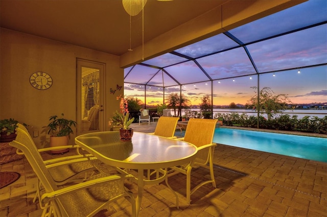view of patio with a water view, an outdoor pool, and a lanai