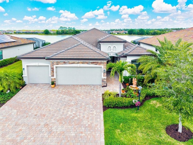 mediterranean / spanish home with a garage, driveway, stone siding, and a tile roof
