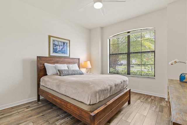 bedroom with multiple windows, wood finished floors, and baseboards