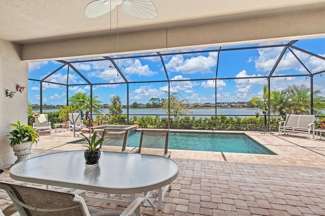 view of pool featuring a patio, a water view, ceiling fan, glass enclosure, and a pool with connected hot tub