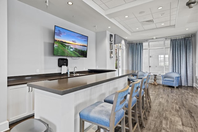 bar featuring wood finished floors, a sink, recessed lighting, a tray ceiling, and a drop ceiling