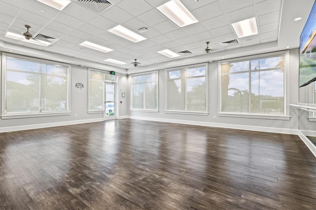 empty room featuring a drop ceiling, wood finished floors, and baseboards
