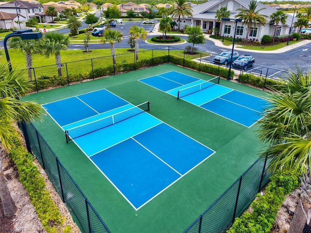 view of tennis court with fence and a residential view
