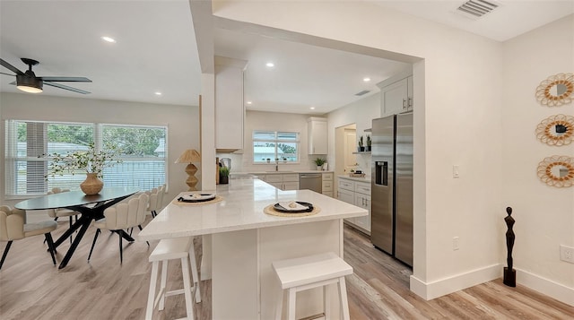 2825 Pinecrest St, Sarasota, FL 34239 - kitchen with appliances with stainless steel finishes, a peninsula, a sink, light wood-type flooring, and a breakfast bar