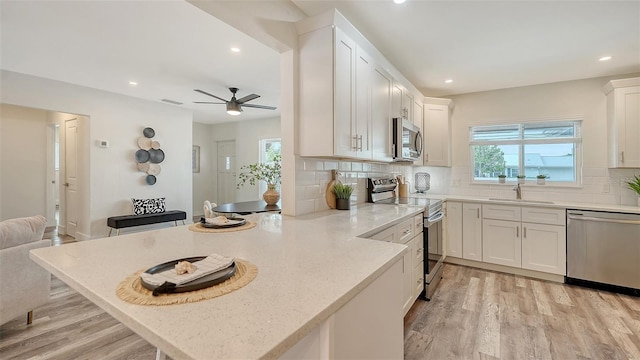 2825 Pinecrest St, Sarasota, FL 34239 - kitchen with stainless steel appliances, ceiling fan, light wood-style floors, a peninsula, and recessed lighting